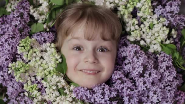 Cute girl dziecko patrząc z bukietu kwiatów lilii wokół jej twarzy - Materiał filmowy, wideo