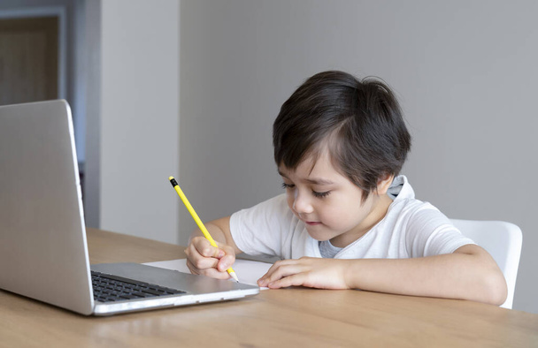 ホームスクール宿題のためのラップトップを使用して子供の自己分離,子は、 covidのロックダウン中にインターネット上で検索情報をコンピュータノートブックを使用して行う,社会的距離, e-ラーニングオンライン教育 - 写真・画像