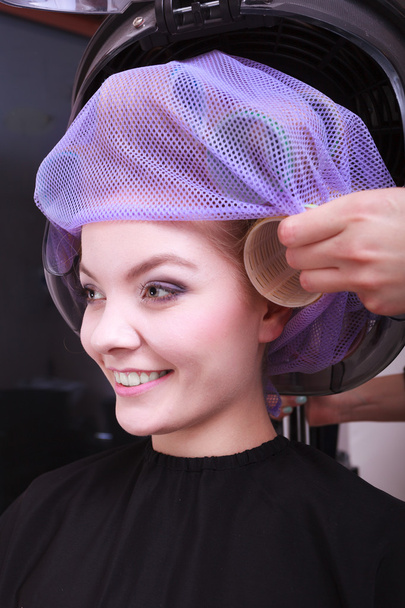 Happy blond girl hair curlers rollers by haidresser in beauty salon - Fotoğraf, Görsel
