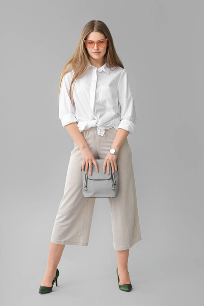Beautiful woman with stylish bag on grey background - Foto, imagen