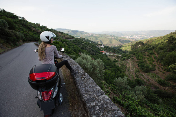 Мотоциклистка едет по змеиной дороге долины Дору, Порту, Португалия
. - Фото, изображение