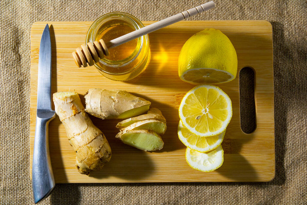 tranches tranchées de citron au gingembre et de miel sur une planche de bois sur un fond de sac. vue de dessus
. - Photo, image