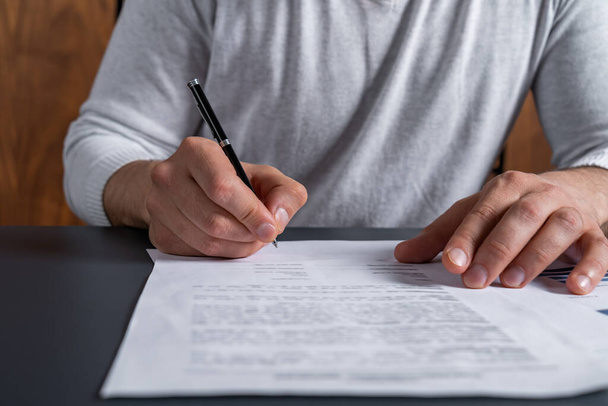 A man signing the mortgage contract at the real property agent office. The concept of entering into legal power to take liabilities. Casual wearing. - Foto, Imagen