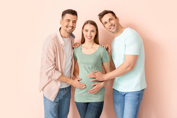 Schwules Paar mit schwangerer Frau auf farbigem Hintergrund - Foto, Bild