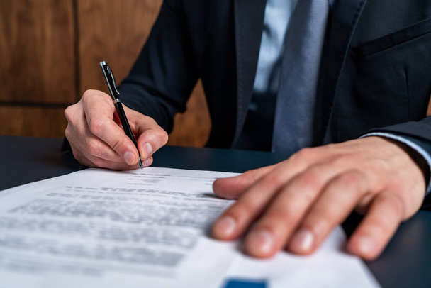A man broker signing the mortgage contract at the real property agent office. The concept of entering into legal power to take liabilities. - Photo, Image