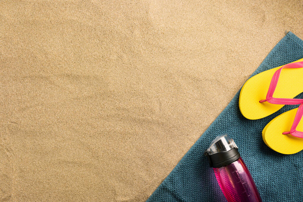 Composição de férias de verão. Flip flops e garrafa de água na praia. Luz dura com sombras
. - Foto, Imagem