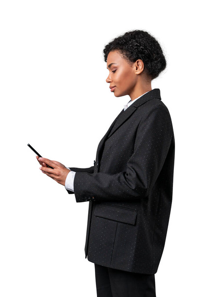 African american woman in black suit looking at mobile phone and texting. Isolated on white background. - Фото, зображення