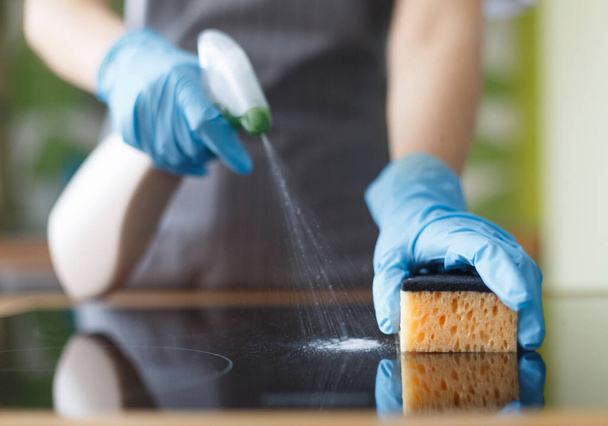 Close up van de vrouw handen in blauw beschermende rubberen handschoenen desinfecteren keuken - Foto, afbeelding