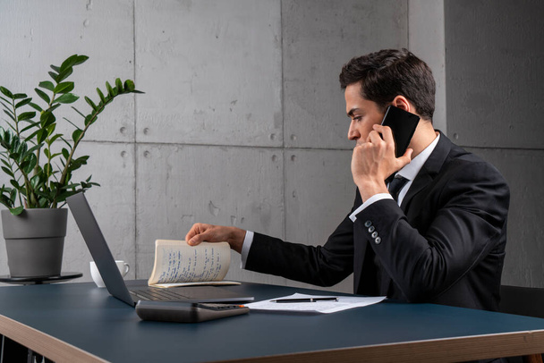 Serious businessman talking on phone in office - Fotó, kép