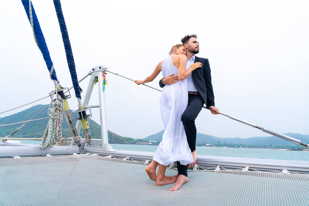 luxury relaxing couple traveler in nice dress and suite stand at part of cruise yacht with background of water sea and white sky. Concept business travel. - Photo, Image