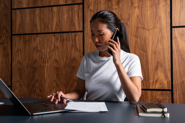 Young Asian businesswoman on phone in office - Foto, immagini