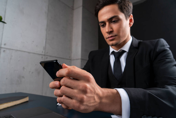 Serious young businessman using phone in office - Foto, Imagem