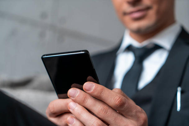 Smiling businessman using phone in office lounge - Photo, Image