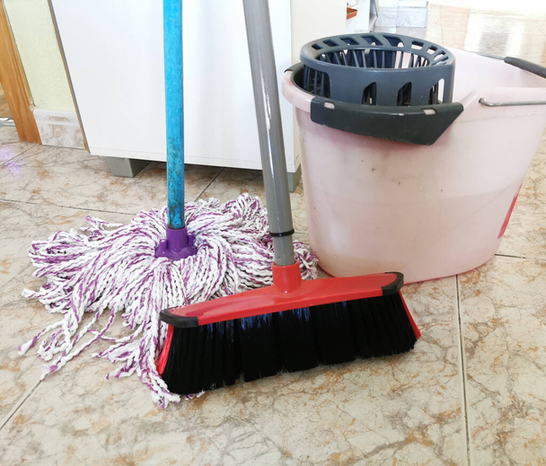 καθαρισμός σπιτιού, κουβάς για σφουγγάρισμα, σφουγγαρίστρα με κλωστές και βούρτσα για σκούπισμα του δαπέδου - Φωτογραφία, εικόνα