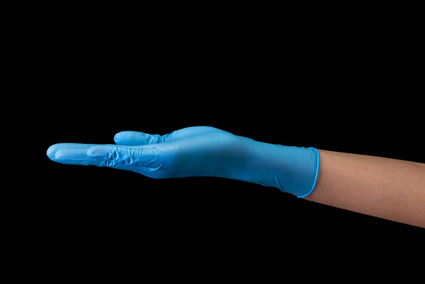 Doctors hand in sterile medical gloves showing palm isolated on black - Photo, Image
