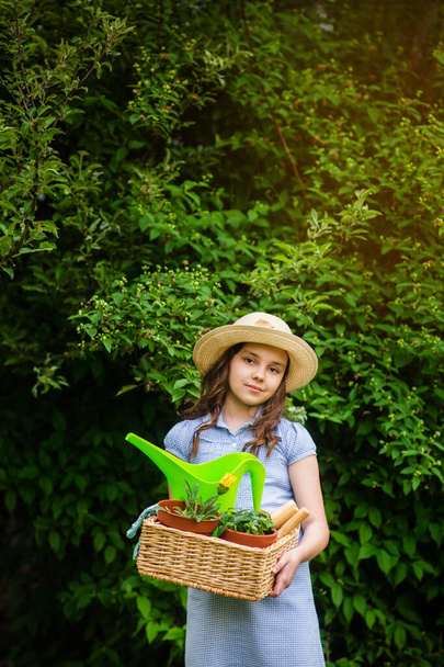 usmívající se roztomilá dívka zahradník drží koš a zahradnické nářadí v zahradě za slunečného dne. Letní aktivity - Fotografie, Obrázek