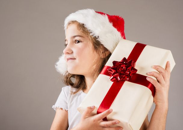 Small girl in santa hat with christmas gift - Foto, immagini