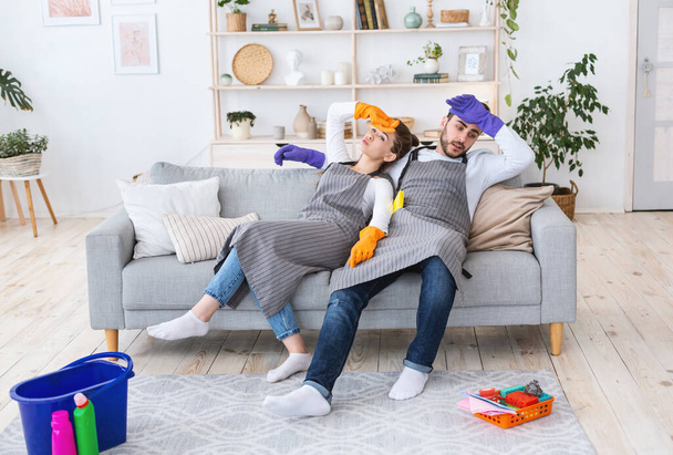 Müde nach dem Putzen. Mann und Frau ruhen sich auf Couch aus - Foto, Bild