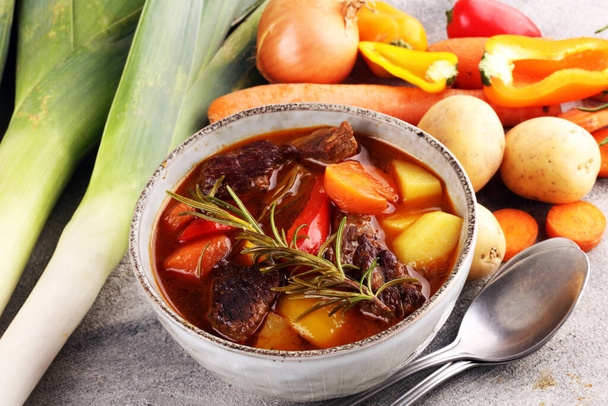 Meat stew with vegetables. Beef stew with potatoes, carrots and herbs on table.  - Photo, Image