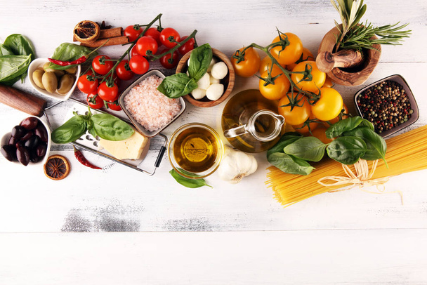 Italian food background with herbs and spices, vine tomatoes, basil, spaghetti, olives, parmesan, olive oil, garlic, peppercorns and rosemary - Foto, Bild