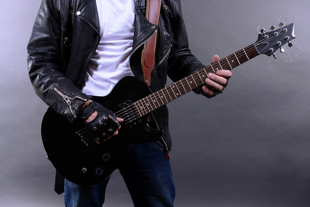 Young musician playing guitar and singing, on dark color background - Foto, Imagem