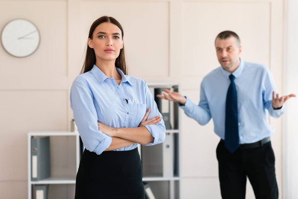 Podnikatel křičí na ženu zaměstnance stojící v moderní kanceláři - Fotografie, Obrázek