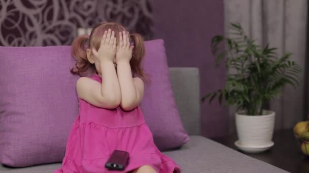 Little child sitting while watching TV. Scared kid girl watch horror movie - Imágenes, Vídeo