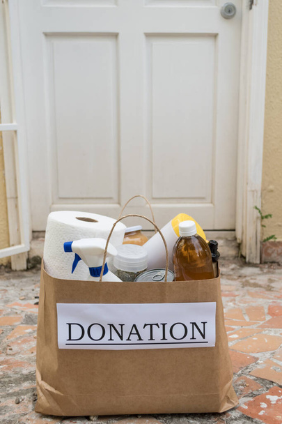 Μια τσάντα δωρεάς με τρόφιμα και προμήθειες καθαρισμού παραδίδεται σε ένα σπίτι κατά τη διάρκεια της πανδημίας Covid-19 / Coronavirus - Φωτογραφία, εικόνα