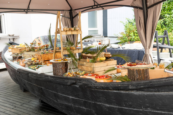 Luxury catering by the pool, food bloggers event, banquet, wedding, festive, hotel brunch buffet arrangement with clean simple design, decorations, boat filled with ice. Modern design and decorations - Фото, зображення