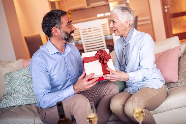 Старший мужчина дарит жене подарок на день рождения. - Фото, изображение
