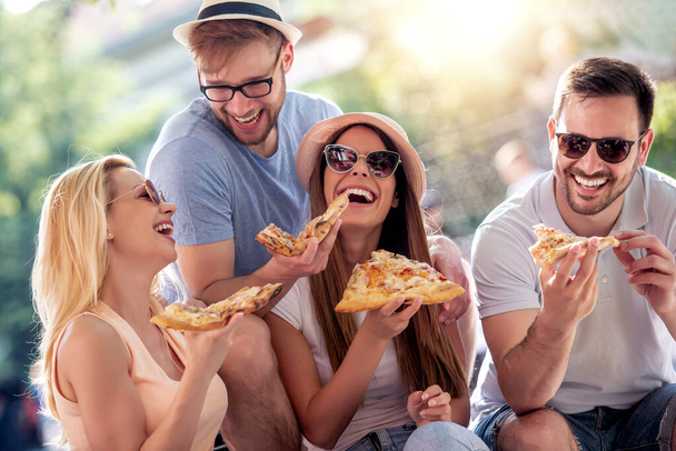 Amigos divirtiéndose y comiendo pizza en la ciudad. - Foto, Imagen