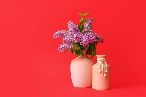 Different vases with bouquet of flowers on color background - Фото, изображение