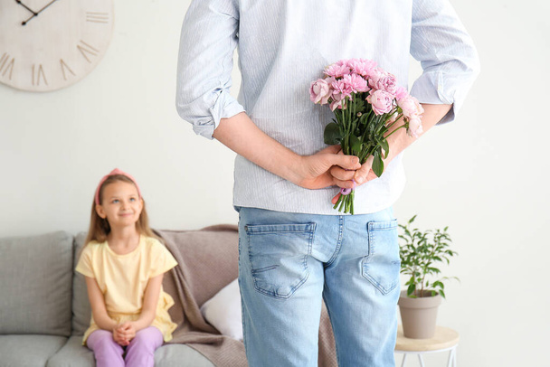 Pai segurando flores para sua filhinha nas costas em casa
 - Foto, Imagem