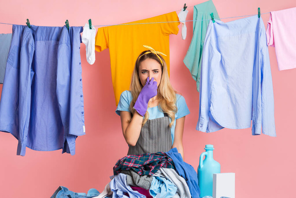 Housewife closes nose in front of heap of dirty clothes - Fotoğraf, Görsel
