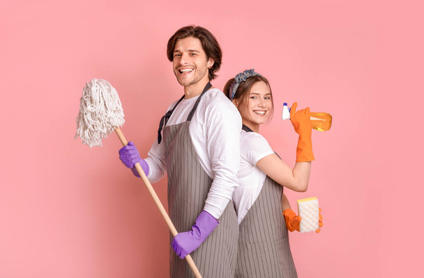 Service de nettoyage professionnel. Sourire homme et femme avec des outils ménagers dans les mains
 - Photo, image