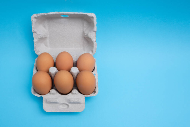 Six pack of eggs in carton on blue background - top view with copy space - Фото, изображение