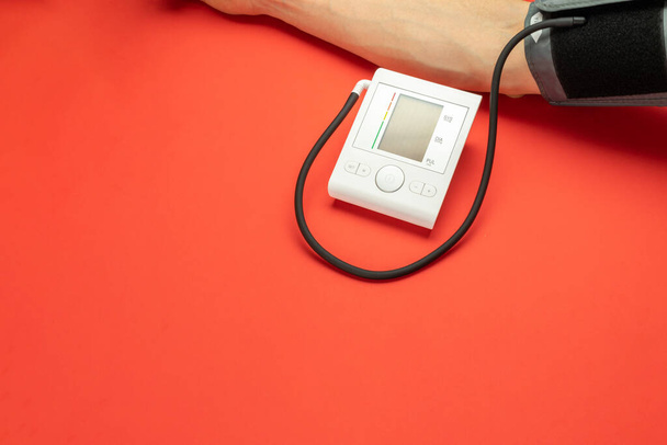 Pressure meter. Patient test hypertension from medical sphygmomanometer. Health monitor for check doctor blood pressure isolated on red background. Man hand cardio control - Photo, Image