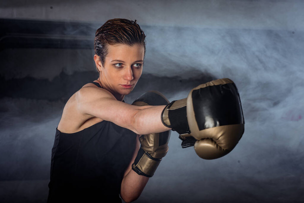 Close-up afbeelding van een vrouwelijke bokser oefenen ponsen met bokshandschoenen - Foto, afbeelding