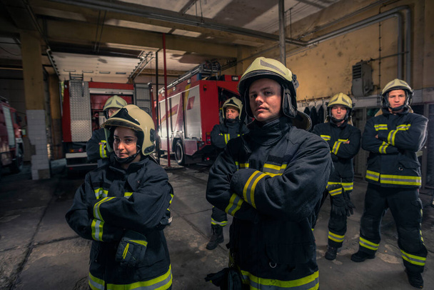 Grupo de bomberos de pie confiados con los brazos cruzados. Bomberos listos para el servicio de emergencia. - Foto, Imagen