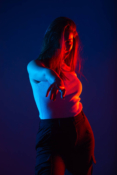 Female model posing in studio with red and blue colors at high contrast. - Valokuva, kuva