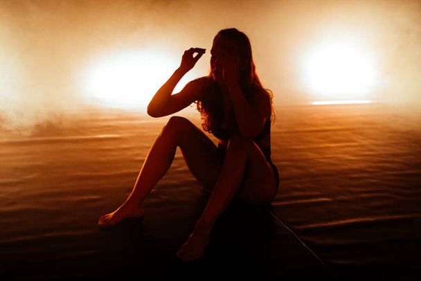 Γυναίκα χορεύτρια μπαλέτου κάθεται στο πάτωμα και ξεκουράζεται μετά την προπόνηση. - Φωτογραφία, εικόνα
