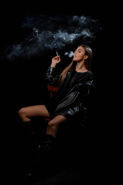 黒スカートと煙のタバコを身に着けているスタイリッシュな若い女性 - 写真・画像