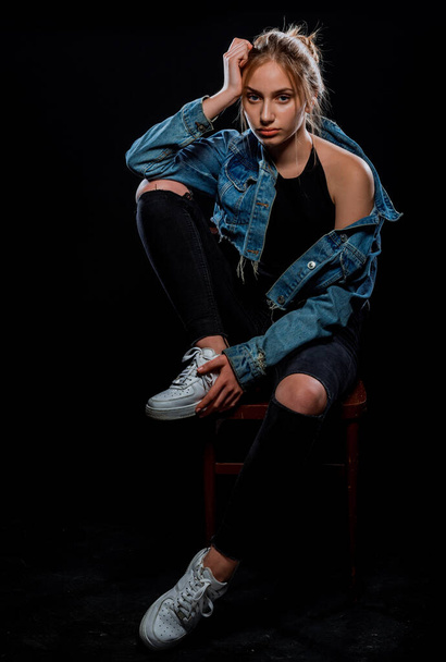 Portret van een mooi vrouwelijk model poserend in trendy denim jas en blauwe jeans - Foto, afbeelding
