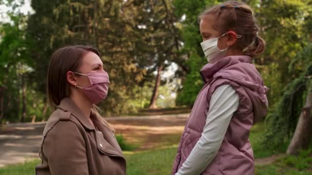 Young mother kisses daughter in a protective medical mask, daughter kisses in response - Footage, Video