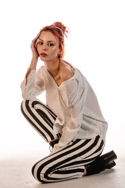 Снимок тела крутой молодой женщины, носящей брюки в современном стиле на белом фоне - Фото, изображение