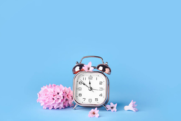 Alarm clock and flowers on color background. Spring time - Photo, Image