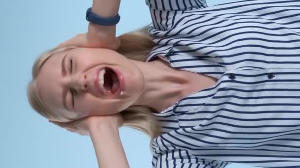 Mujer desesperada asustada gritando y cubriendo oídos sobre fondo azul
 - Metraje, vídeo