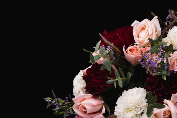 A closeup shot of a luxurious bouquet of pink roses and white, red dahlias on a black background - Foto, Imagen