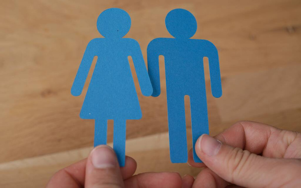 A closeup shot of a man holding blue female and male signs on a wooden background - Foto, imagen