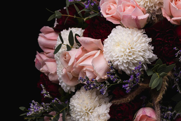 A closeup shot of a luxurious bouquet of pink roses and white flowers on a black background - Фото, зображення